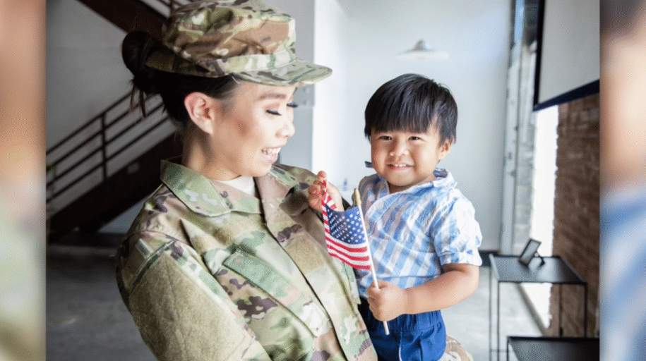 Smiling woman in uniform holds child with American flag.